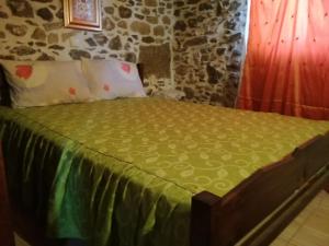 a bed with a green comforter and pillows at The Rock in Kapetanianá