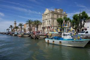 un barco sentado en el agua junto a un edificio en L'Imperial, en Le Grau-du-Roi