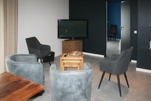 a living room with chairs and a tv and a table at Les Centaurines in Saint-Siffret