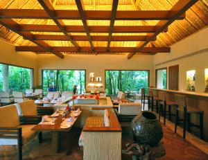 a restaurant with tables and chairs in a room with windows at Vedic Village Spa Resort Kolkata in Kolkata