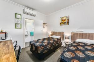 a hotel room with two beds and a table and a kitchen at Rest Motels in Naracoorte