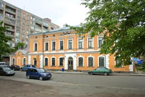 duży pomarańczowy budynek z samochodami zaparkowanymi przed nim w obiekcie Letuchaya Mysh Hotel w mieście Wyborg