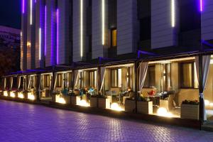 a building with people sitting at tables at night at Renion Park Hotel in Almaty