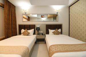 a hotel room with two beds and a mirror at Aristocrat Hotel in Kolkata