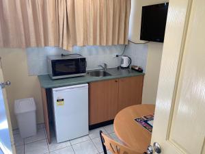 Il comprend une petite cuisine équipée d'un évier et d'un four micro-ondes. dans l'établissement John Oxley Motel, à Port Macquarie