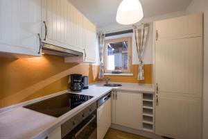 een keuken met witte kasten, een wastafel en een raam bij Haus Bauer in Pertisau