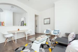 una sala de estar blanca con mesa y sillas en STUNNING SYDNEY HOME 4, en Sídney