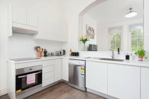 cocina blanca con fregadero y lavavajillas en STUNNING SYDNEY HOME 4 en Sídney