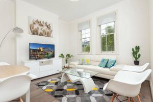 un soggiorno bianco con divano bianco e tavolo di STUNNING SYDNEY HOME 6 a Sydney