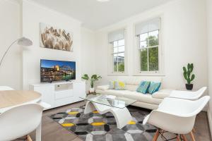 a white living room with a white couch and a table at STUNNING SYDNEY HOME 10 in Sydney