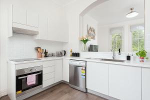 cocina blanca con fregadero y lavavajillas en STUNNING SYDNEY HOME 10 en Sídney