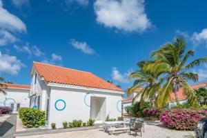 a white building with palm trees and a blue sky at Marazul Dive Resort in Sabana Westpunt