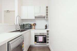 una cocina blanca con armarios blancos y fregadero en STUNNING SYDNEY HOME 11, en Sídney