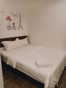 a bed with white sheets and a bicycle on the wall at Cozy Riverside Hotel in Melaka