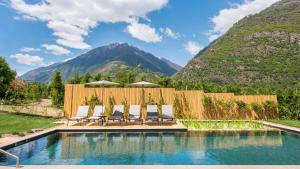 a pool with chairs and a fence and mountains at Cirna Gentle Luxury Lodges in Naturno