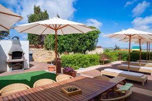 a patio with a table and umbrellas and a putting green at Villa Munqar in Żurrieq