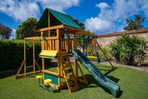 a wooden playset with a slide and a playground at Villa Munqar in Żurrieq