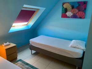 ein blaues Zimmer mit einem Bett und einem Fenster in der Unterkunft Villa D'este in De Haan