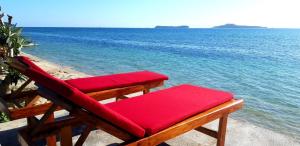 a red bench sitting on the beach near the water at Alden Beach House in Sekotong