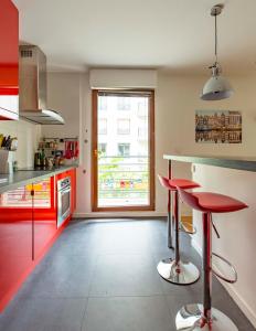 a kitchen with red cabinets and red bar stools at Veeve - Modern Brights in Paris