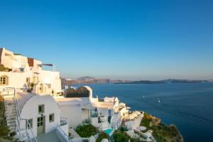 a group of white buildings on the edge of the water at Kaleidoscope Cave Houses in Oia