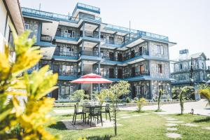 a building with a table and an umbrella in front of it at Hotel K2 Pokhara in Pokhara