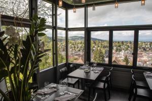 um restaurante com mesas e cadeiras e janelas grandes em Hotel Restaurant Falkenburg em St. Gallen