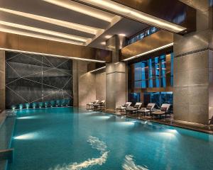 a swimming pool in a building with chairs in it at Four Seasons Hotel Shenzhen in Shenzhen