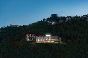 a building on top of a hill with lights on at Larisa Shimla in Shimla