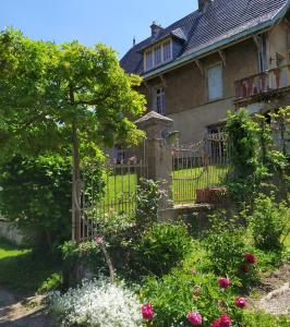 an old house with a gate and flowers at La Fée des Eaux in Vernaison