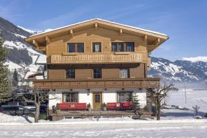 une grande maison en bois avec des bancs rouges dans la neige dans l'établissement Haus Kreidl, à Schwendau