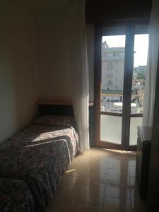 een slaapkamer met een bed en een raam met een balkon bij Maxi Heron in Lido di Jesolo