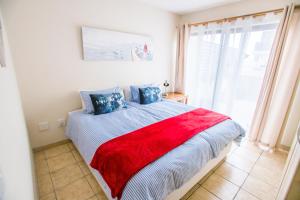 een slaapkamer met een bed met een rode deken erop bij Bianka's Self-Catering Apartment in Swakopmund +15 foto's