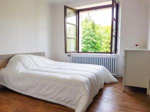 ein weißes Bett in einem Zimmer mit Fenster in der Unterkunft Grande maison de charme Bretonne in Québriac