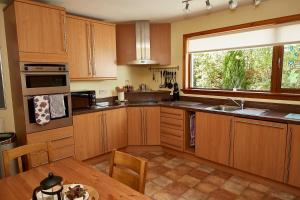 a kitchen with wooden cabinets and a large window at Rowans Inverness in Inverness
