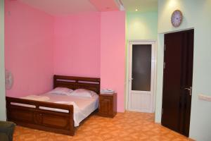 1 dormitorio con cama y pared de color rosa en Manand Hotel en Ereván