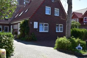 a red brick house with a tree in front of it at Möwenhaus in Wangerland