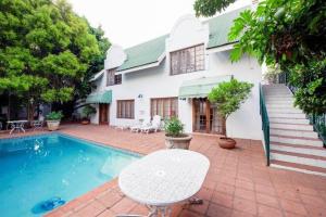 a white house with a swimming pool and a table at Birdwood Boutique Estate in Pretoria