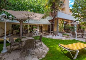 een patio met een tafel en stoelen en een parasol bij Hostal Gallet in Roses