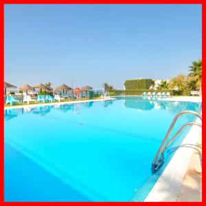 a large swimming pool with blue water and chairs at Apartamentos Guga RTA A CA 00267 AT Edif Complejo 2 Llaves Playa in Conil de la Frontera