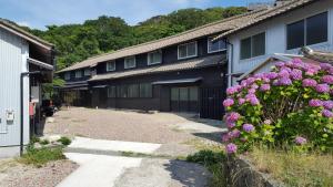 Une rangée de maisons avec des fleurs violettes devant elles dans l'établissement Asobi Lodge, à Kyōtango