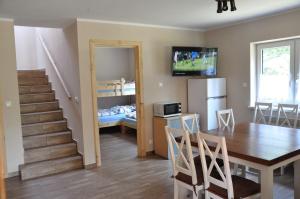 a kitchen and dining room with a table and a room with a staircase at Domki w Radawie in Radawa