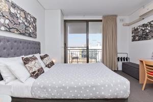 a bedroom with a bed and a table and a balcony at Central City Exclusive Apartments in Perth