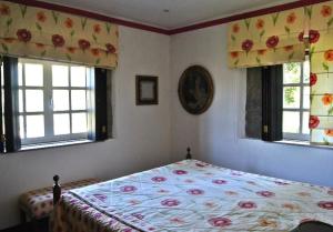 um quarto com uma cama e duas janelas em Quinta do Freixieiro em Cinfães