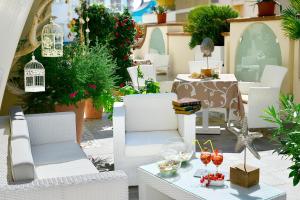 a patio with white chairs and a table with drinks on it at Hotel La Conchiglia in Bellaria-Igea Marina