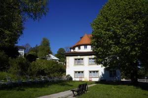 una casa blanca con un banco delante en Villa am Park en Bad Tölz