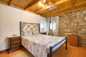 a bedroom with a bed and a stone wall at Quinta do Rio Homem in Caldelas