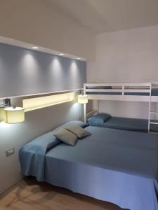 a bedroom with a large bed with blue sheets at Hotel Perla Gaia in San Vito lo Capo