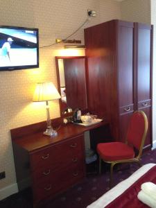a hotel room with a desk and a tv on the wall at Avon Hotel in London