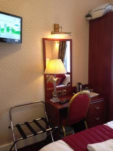 a hotel room with a desk and a lamp and a mirror at Avon Hotel in London